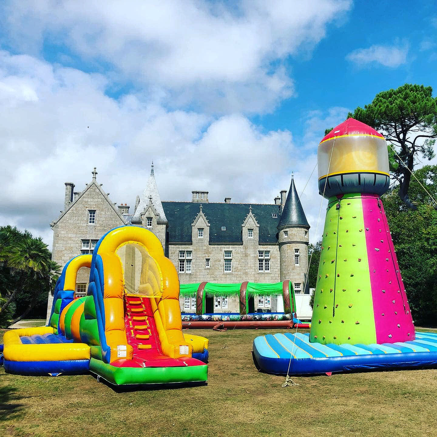 Structures gonflables colorées, Wipe Out, Phare d'escalade et ventrigliss devant un château