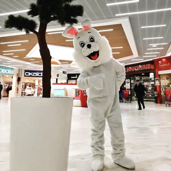 Mascotte lapin dans une galerie commerciale qui pose à côté d'une plante, Jump'O'Clown