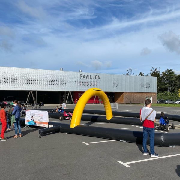 Structure gonflable, circuit de karting gonflable devant le pavillon à Quimper, avec des enfants sur les karting, Jump'O'Clown