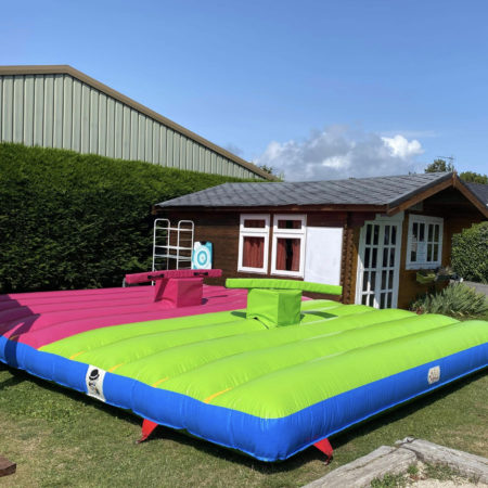 Structure gonflable, animation gonflable, combat de joutes vert et rose, dans un jardin devant un cabanon, Jump'O'Clown