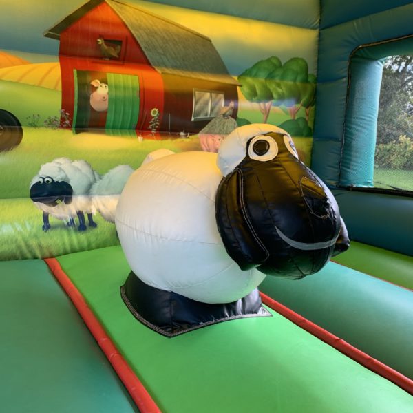 Intérieur de la Structure gonflable, château gonflable, maison toboggan ferme avec obstacle mouton noir et blanc vert avec un fond de dessins d'animaux de la ferme, dans un jardin, Jump'O'Clown